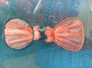 The pleated shells stitched down, left with blue seed beads and right with pink seed beads.